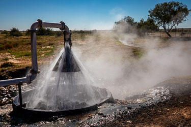 Hot water surges from an artesian bore at Birdsville’s geothermal power station, venting steam into the morning air. Drawn from the Great Artesian Basin, this naturally heated flow drives turbines that supply most of the town’s electricity — a quiet triumph of outback engineering.[1054]