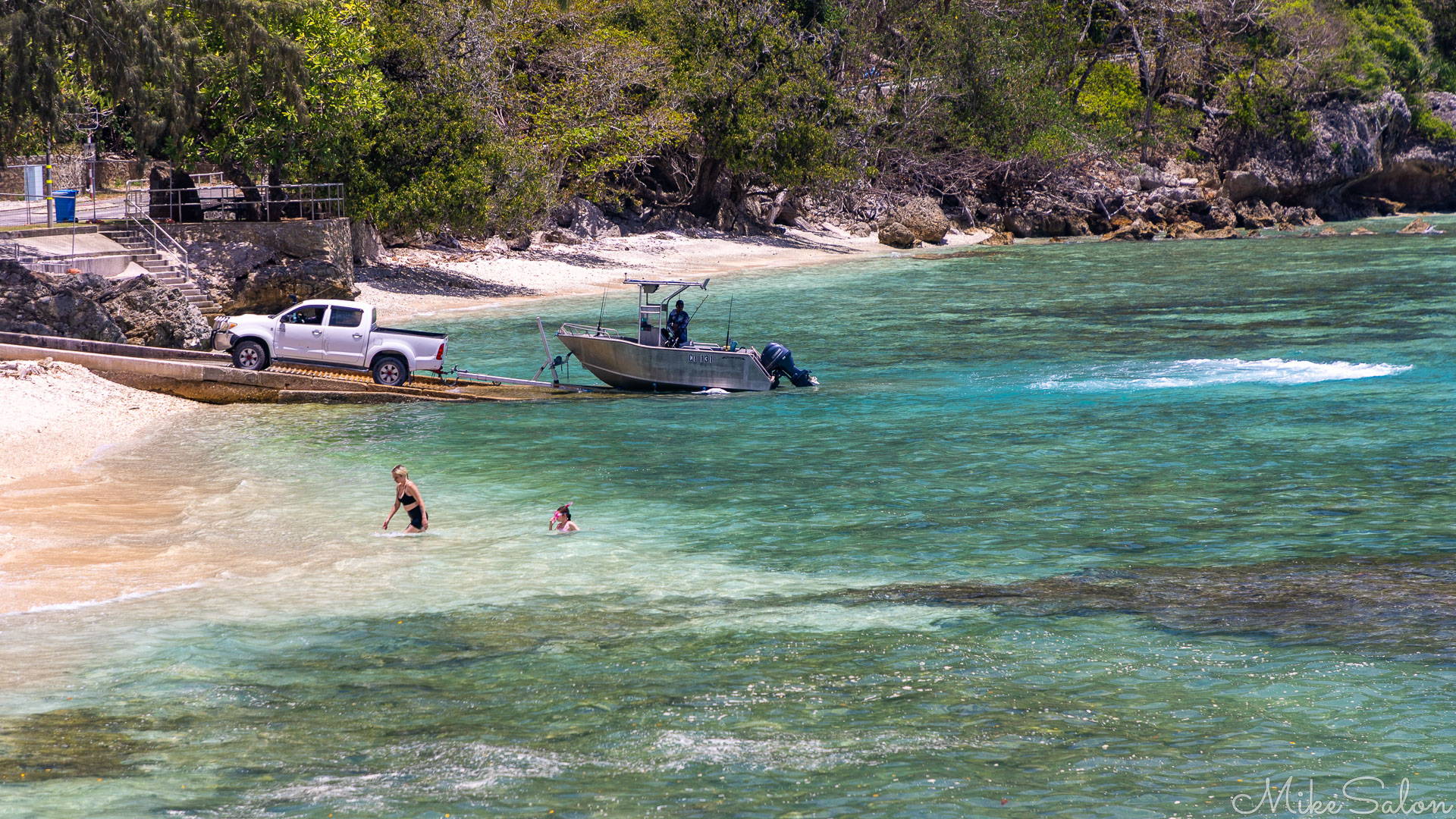 Two swimmers and a fishing boat launch at Flying Fish Cove. [9854]
