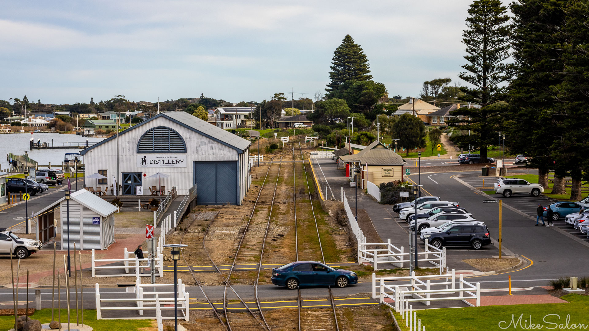Goolwa Railway Station with a car crossing the lines and a Distillery outlet in an old shed. [2160]