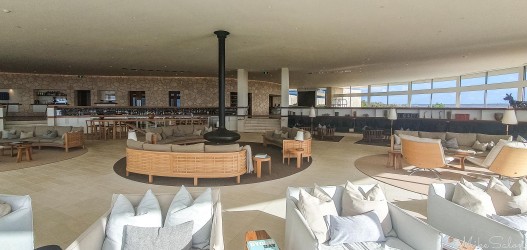 Interior of a great common room, with comfortable furniture and a floating fireplace in the centre. [4511]