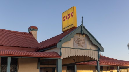 Exterior of Maidens Hotel with red roof and XXXX signage.