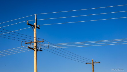 Utility poles and power lines under a cloudless sky.