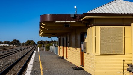 Yellow railway station building beside tracks.
