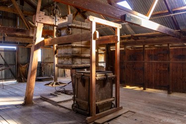 Interior of woolshed showing wooden beams and old shearing equipment.