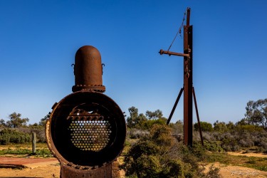 Large rusted cylindrical boiler standing outdoors.