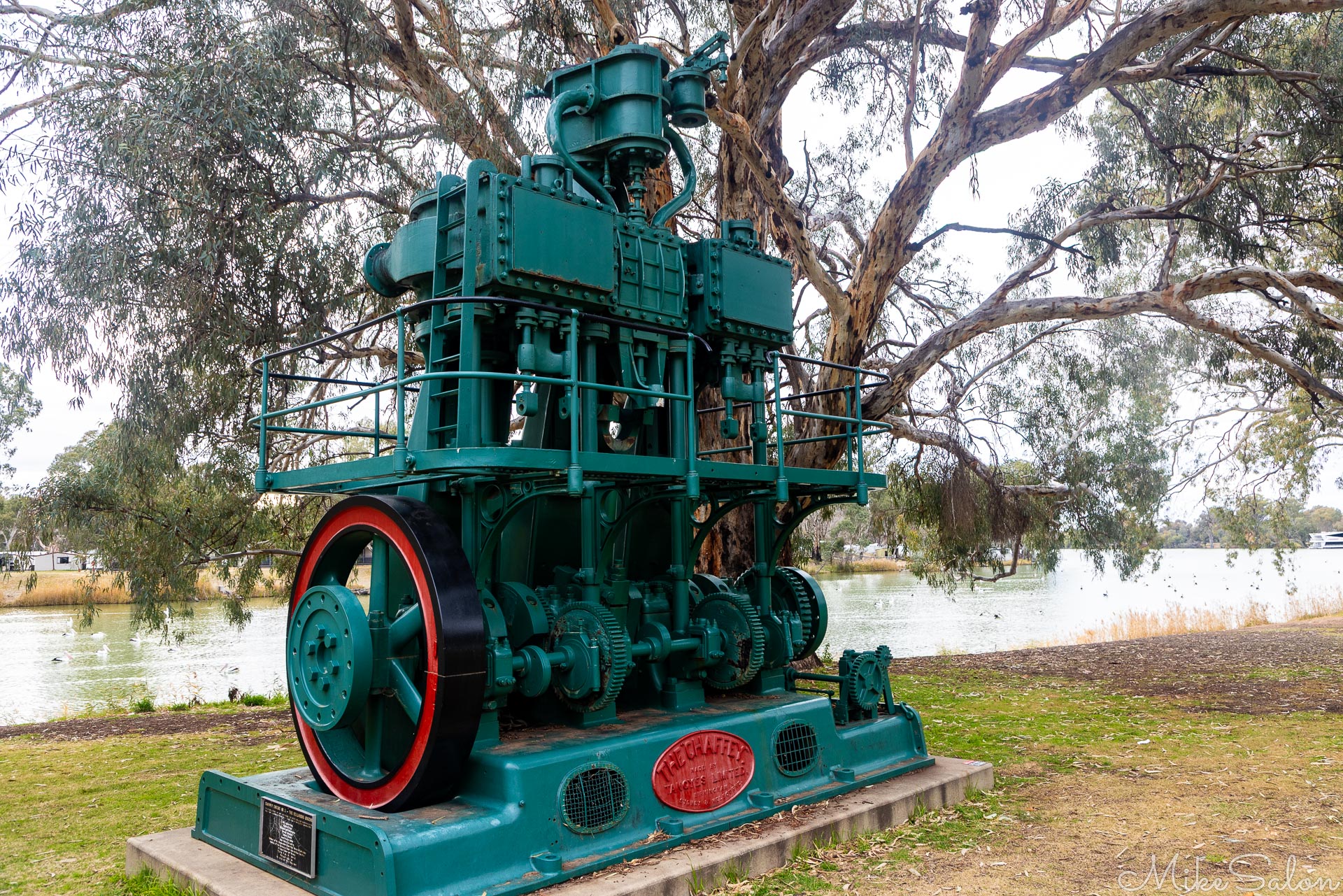 Large historic green and red water pump displayed outdoors.