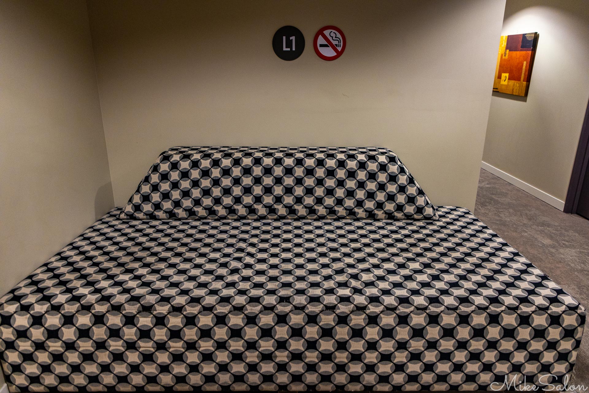 Black‑and‑white checkered couch against beige wall with signage and framed artwork.