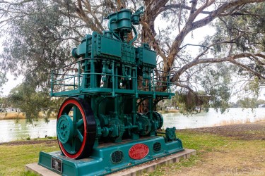 Large historic green and red water pump displayed outdoors.