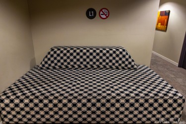 Black‑and‑white checkered couch against beige wall with signage and framed artwork.