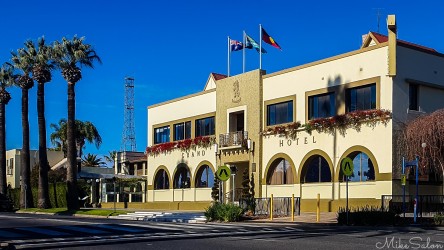 Two‑storey hotel building with arched windows and flags.