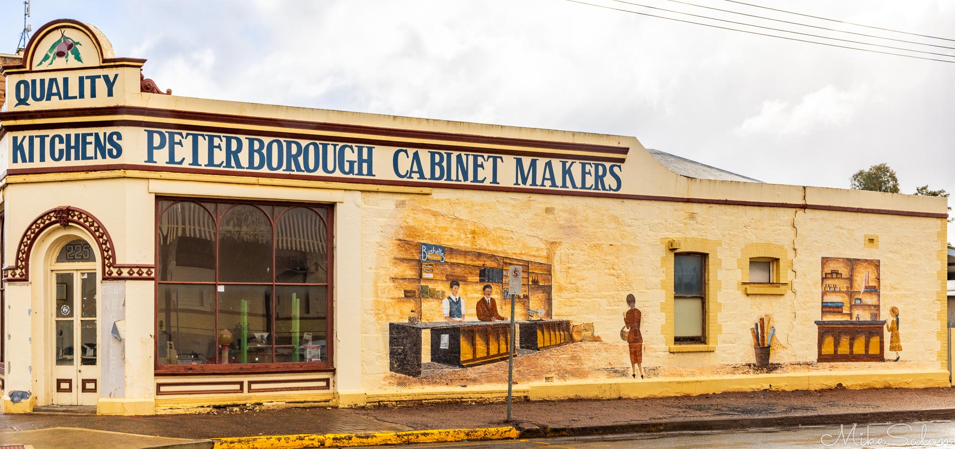 Single‑storey building with mural of people and furniture, sign reading "Peterborough Cabinet Makers."