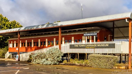 Two‑storey museum building with corrugated roof and sign reading "Peterborough The Town Carriage Museum."