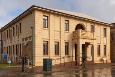Beige two‑storey YMCA building with arched entrance and wet pavement.