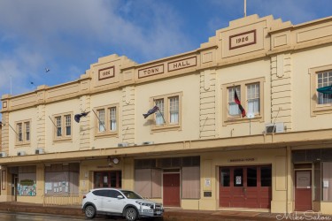 Cream‑coloured town hall with decorative façade and parked car in front.