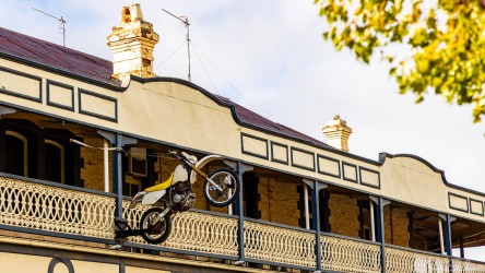 Motorbike mounted on upper balcony of heritage building with iron railings.