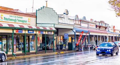 Row of heritage shops along wet street with parked cars and visible signage.