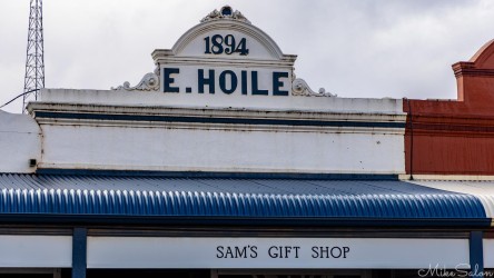 White building with blue trim and sign reading "E. Hoile 1894" and "Sam