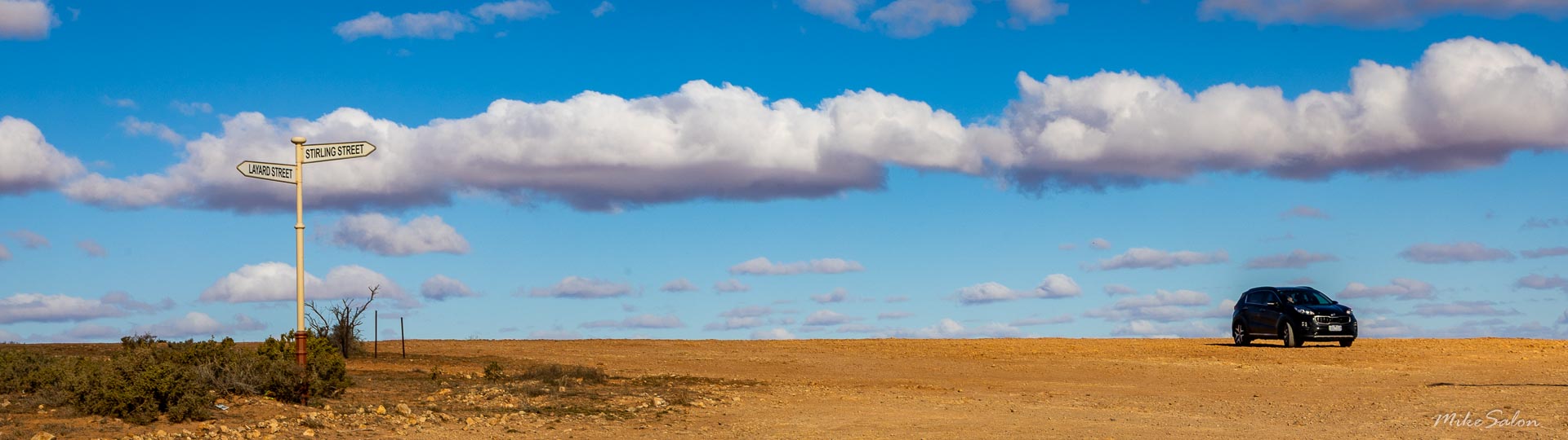 Panorama of a desert horizon, a car parked at one end.