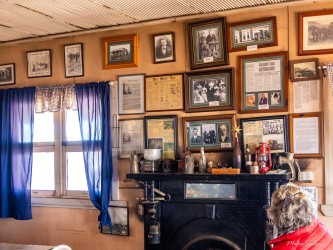  Interior room with framed photos, blue curtains, and fireplace, person seated near display.