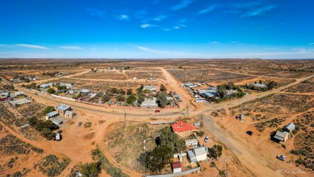 Aerial view of Silverton showing dirt roads, small buildings, and surrounding desert under clear blue sky.