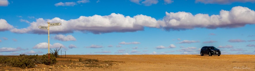 Panorama of a desert horizon, a car parked at one end.