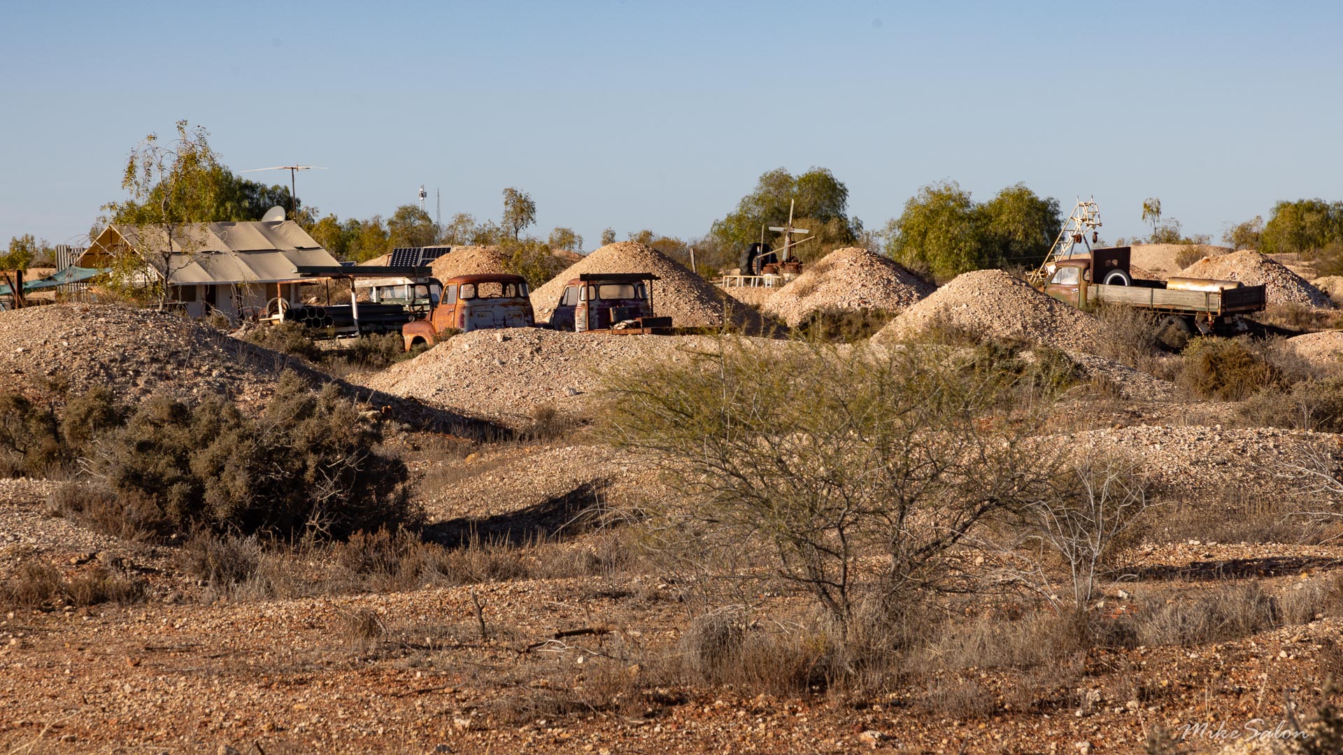 Tailings heaps, old vehicles and shanties make up this opal mining camp. [2177]