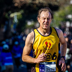 A Terrigal Trotters runner grimaces through the pain at the 32 km mark, his expression matching the slogan on his shirt — “De Agony of De Feet.” The marathon’s toughest stretch brings out both endurance and irony in equal measure. [3959]