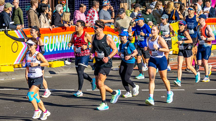 Marathon runners climb Oxford Street past Taylor Square at the 18 km mark, framed by the rainbow “Running with Pride” banner and the cheers of the crowd. The scene captures Sydney’s unique blend of endurance and celebration. [3911]