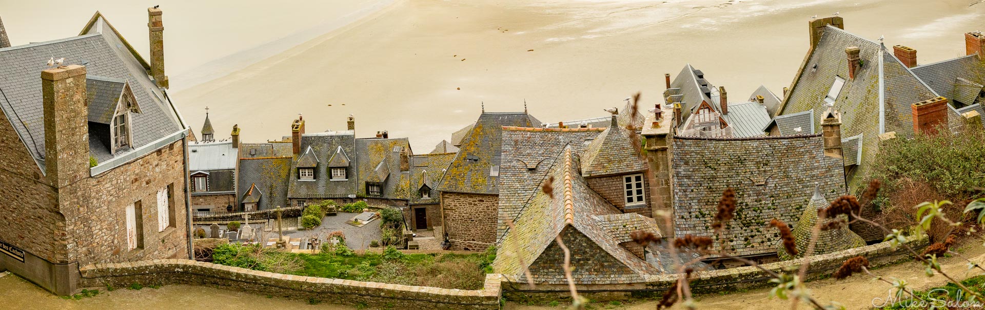 Mont Saint-Michel : Houses and shops of the old village overlook the low tide mudflats of the bay. (_D0A5280-Pano.jpg)<br>Camera: Canon EOS 5D Mark IV