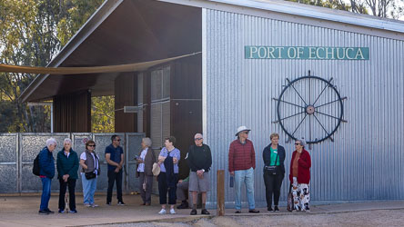 Group of Australian Star passengers standing outside the Port of Echuca visitor centre with corrugated metal walls, ship