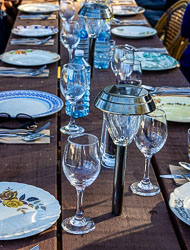 Outdoor long wooden table laid with assorted vintage plates, wine glasses, and solar lanterns for a communal meal at Layfield Lane.