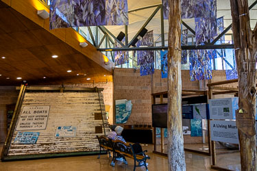 Interior of Murray River visitor centre showing a large timber trestle from the old Mildura weir, interpretive panels, and hanging artworks under natural light.