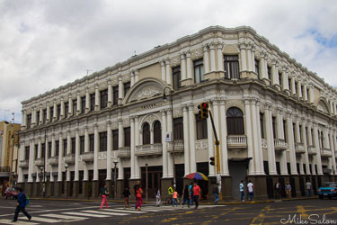 Corner view of the Teatro Melico Salazar in San José, Costa Rica, showing its light‑coloured Beaux‑Arts façade with arched windows and decorative columns under an overcast sky.