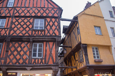 Timber‑framed medieval houses in Dreux, France, leaning toward each other across a narrow street with colourful façades.